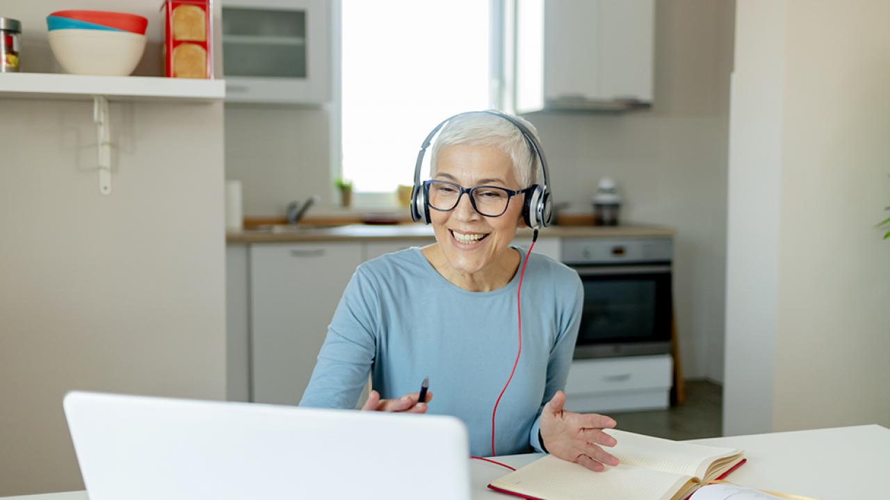 senior woman with headphones on sitting at laptop