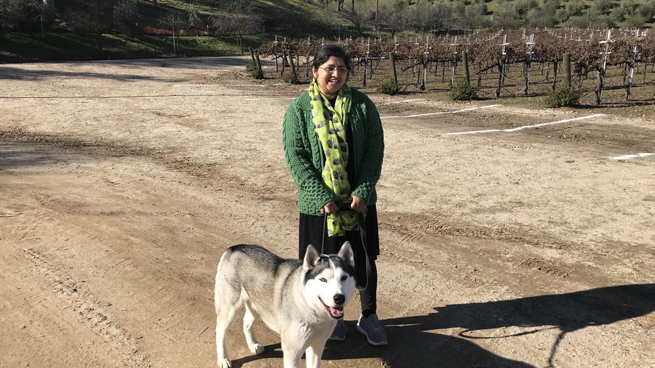 UC Davis Winemaking Certificate program grad Purnima Sreenivasan poses with her dog in a vineyard